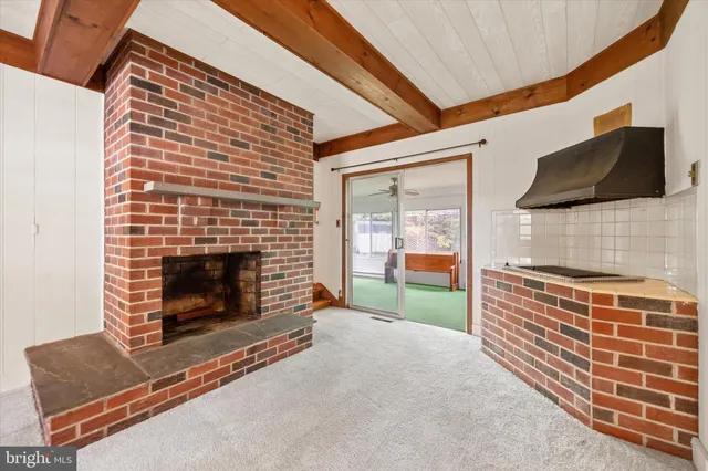 a view of an empty room with wooden floor fireplace and a window