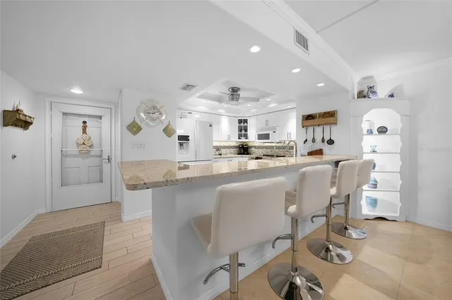 a dining area with stainless steel appliances kitchen island granite countertop a dining table chairs and a refrigerator