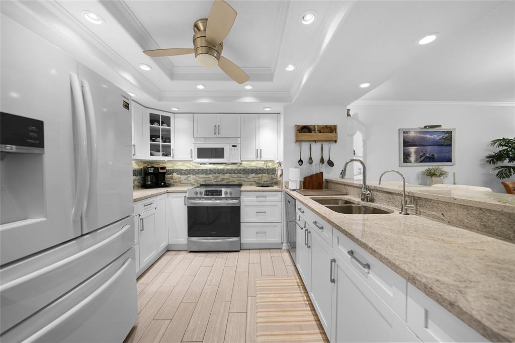 601 Shreve Street, Unit 16A Punta Gorda, FL 33950 - Photo 10 of 52 a large kitchen with stainless steel appliances granite countertop a lot of white cabinets a sink dishwasher and a stove with wooden floor