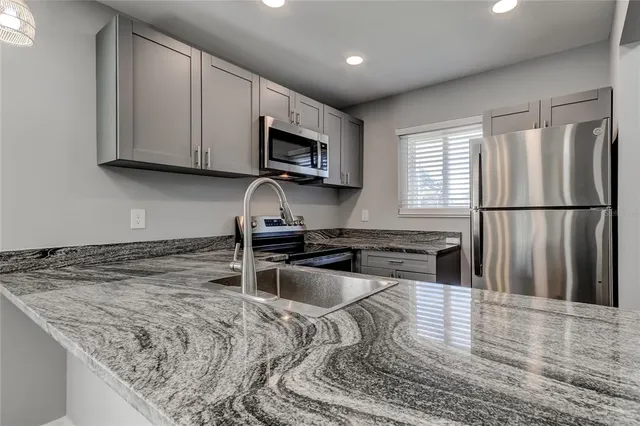 a kitchen with stainless steel appliances granite countertop a stove a sink and a microwave