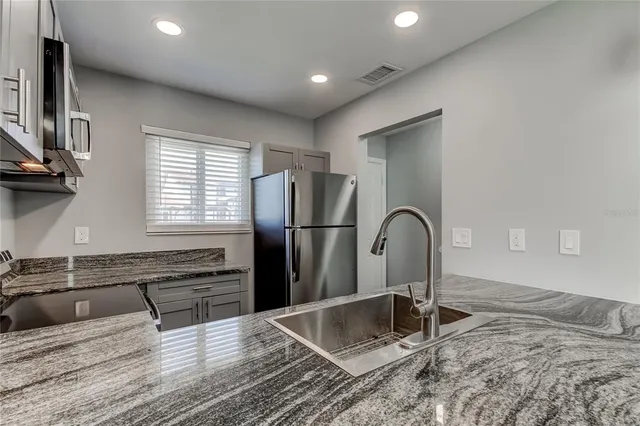 a kitchen with granite countertop a refrigerator and a sink