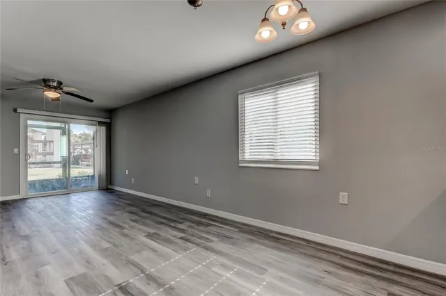 a view of an empty room with a window and wooden floor