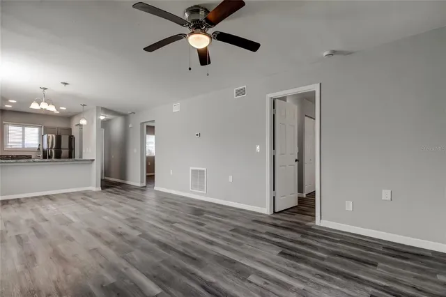 an empty room with wooden floor and a ceiling fan