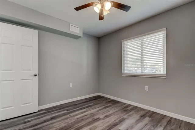 a view of an empty room with a window and wooden floor