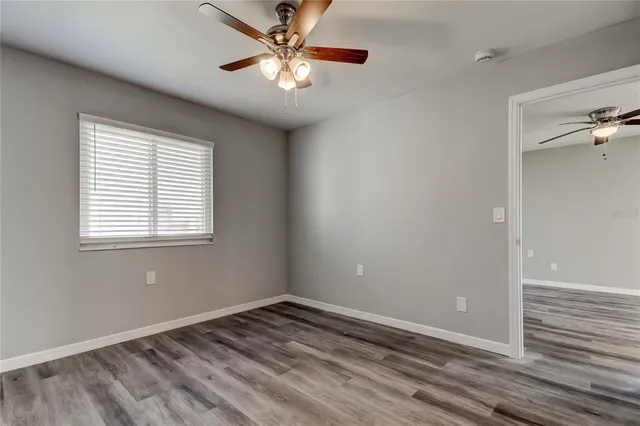 a view of empty room with wooden floor and fan