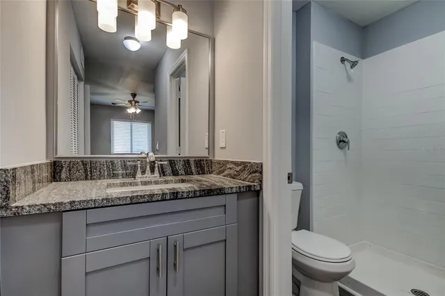 a bathroom with a granite countertop sink a toilet and a mirror