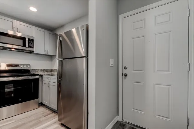 a kitchen with stainless steel appliances granite countertop white cabinets and refrigerator