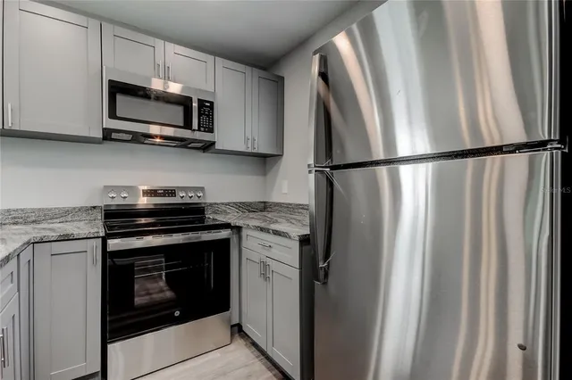 a kitchen with stainless steel appliances granite countertop a refrigerator stove and microwave