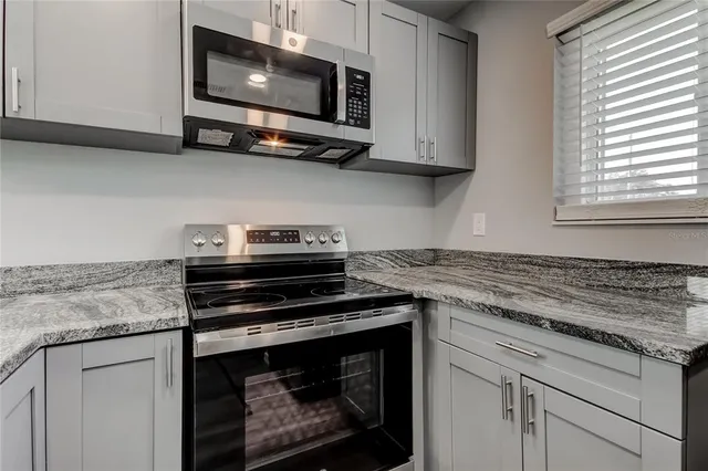 a kitchen with stainless steel appliances granite countertop white cabinets granite counter tops and a wooden floor