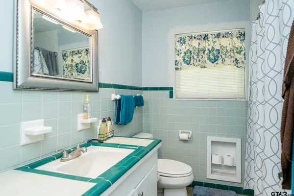 a bathroom with a granite countertop sink mirror vanity and toilet