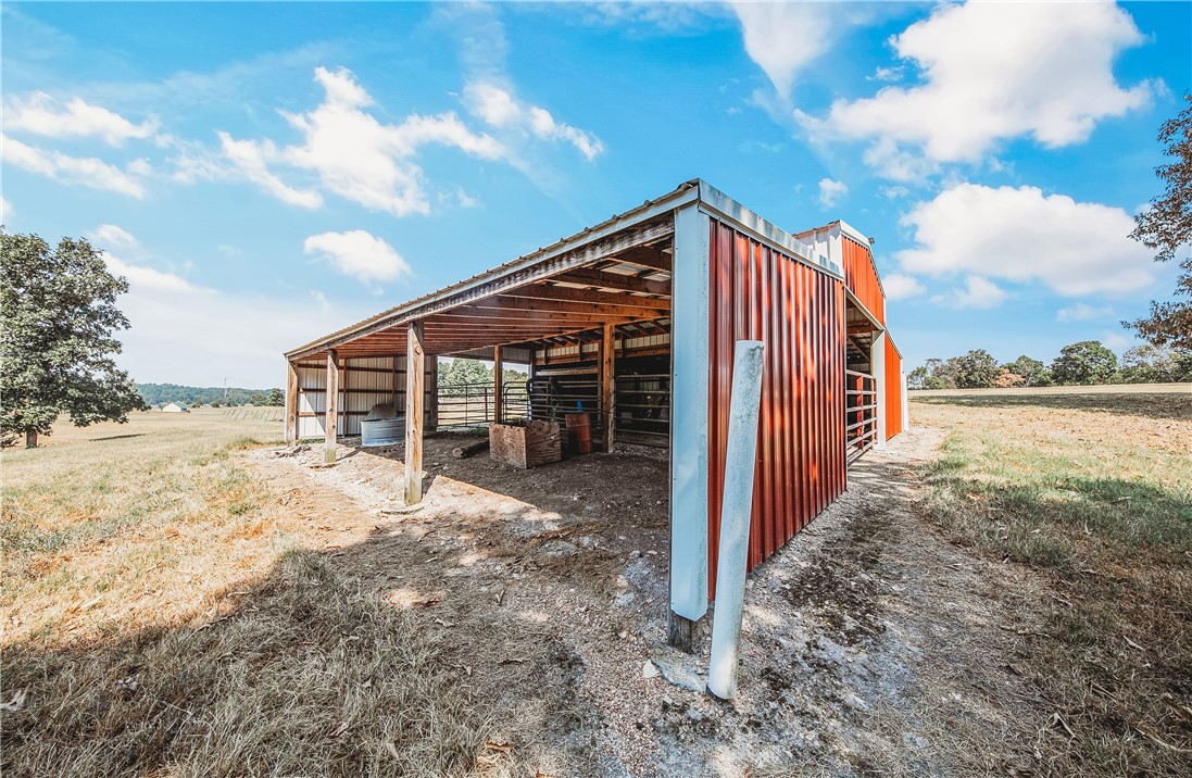 21587 West Hickory Flat Road Springdale, AR 72764 - Photo 41 of 45 36' × 36' general-purpose barn with covered livestock areas, surrounded by open pasture and scenic countryside.