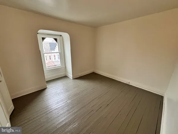 an empty room with wooden floor and mirror