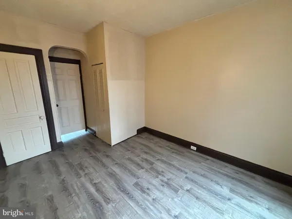 an empty room with wooden floor and mirror