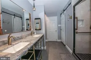 a en suite bathroom with a granite countertop sink a mirror and shower
