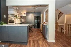 a kitchen with stainless steel appliances granite countertop a refrigerator a sink and wooden floors