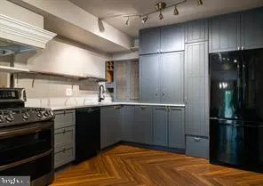 a kitchen with a sink stainless steel appliances wooden floor and cabinets