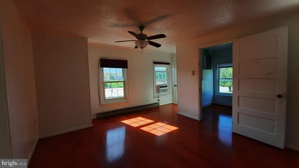 a view of empty room with wooden floor and fan