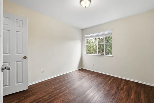 an empty room with wooden floor and windows