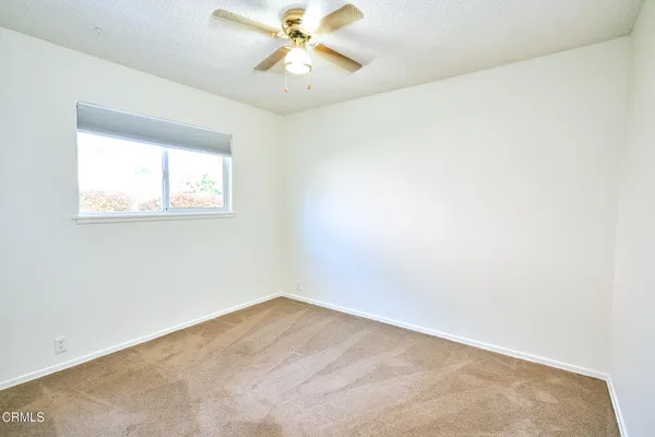 an empty room with wooden floor chandelier fan and windows