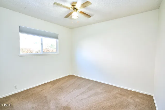 an empty room with wooden floor chandelier fan and windows