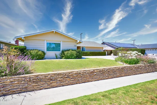a front view of a house with a yard and potted plants