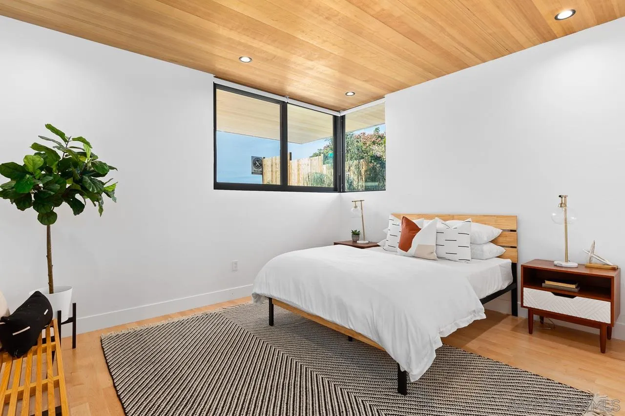 605 Cornish Drive Encinitas, CA 92024 - Photo 19 of 32 a bedroom with a bed a mirror and a potted plant