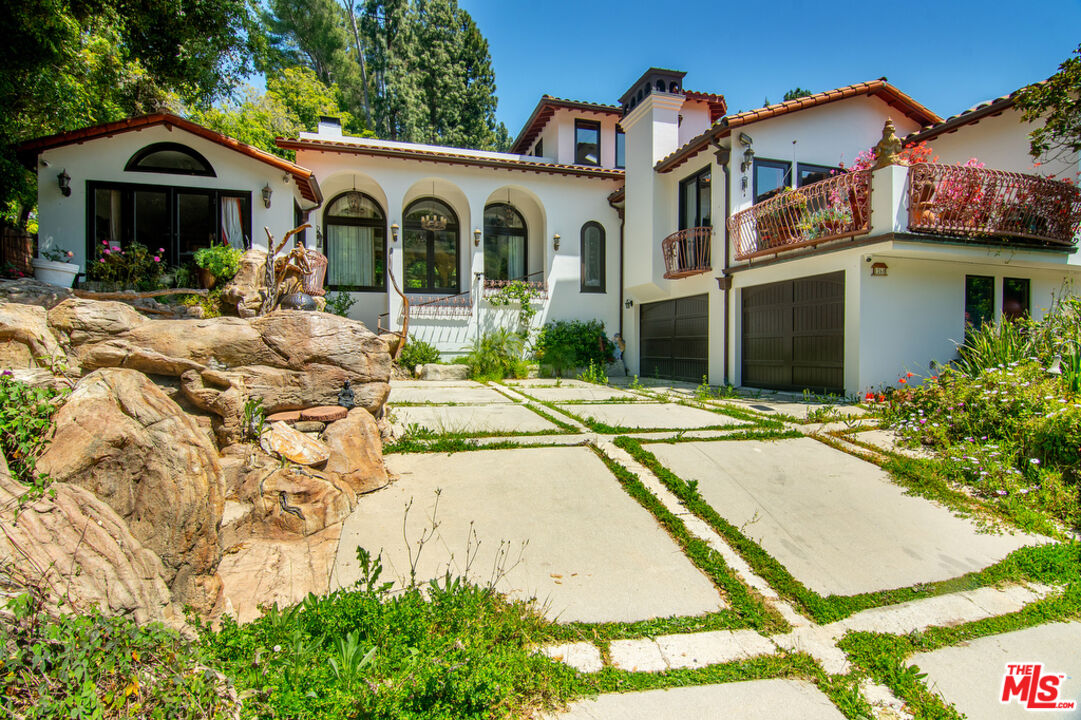 1260 Roscomare Road Los Angeles, CA 90077 - Photo 7 of 75 a view of a white house with large windows and a table and chairs under an umbrella