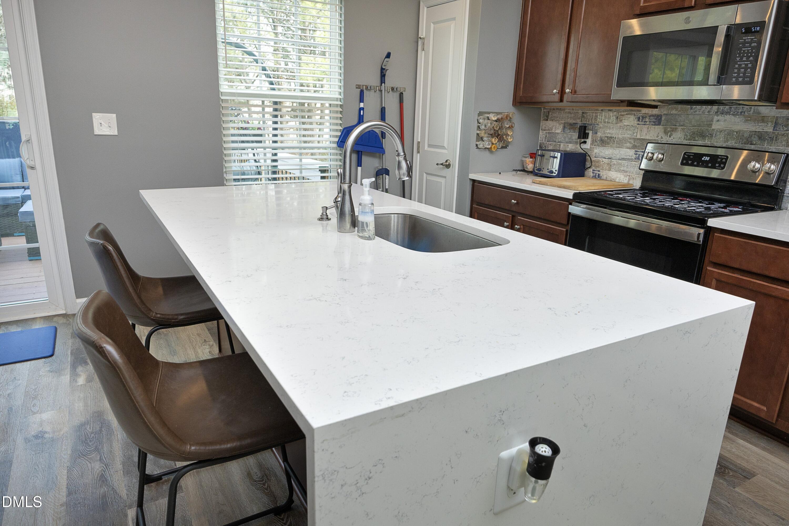 8716 Red Canyon Way Raleigh, NC 27616 - Photo 11 of 36 a kitchen with a table chairs a stove and a microwave