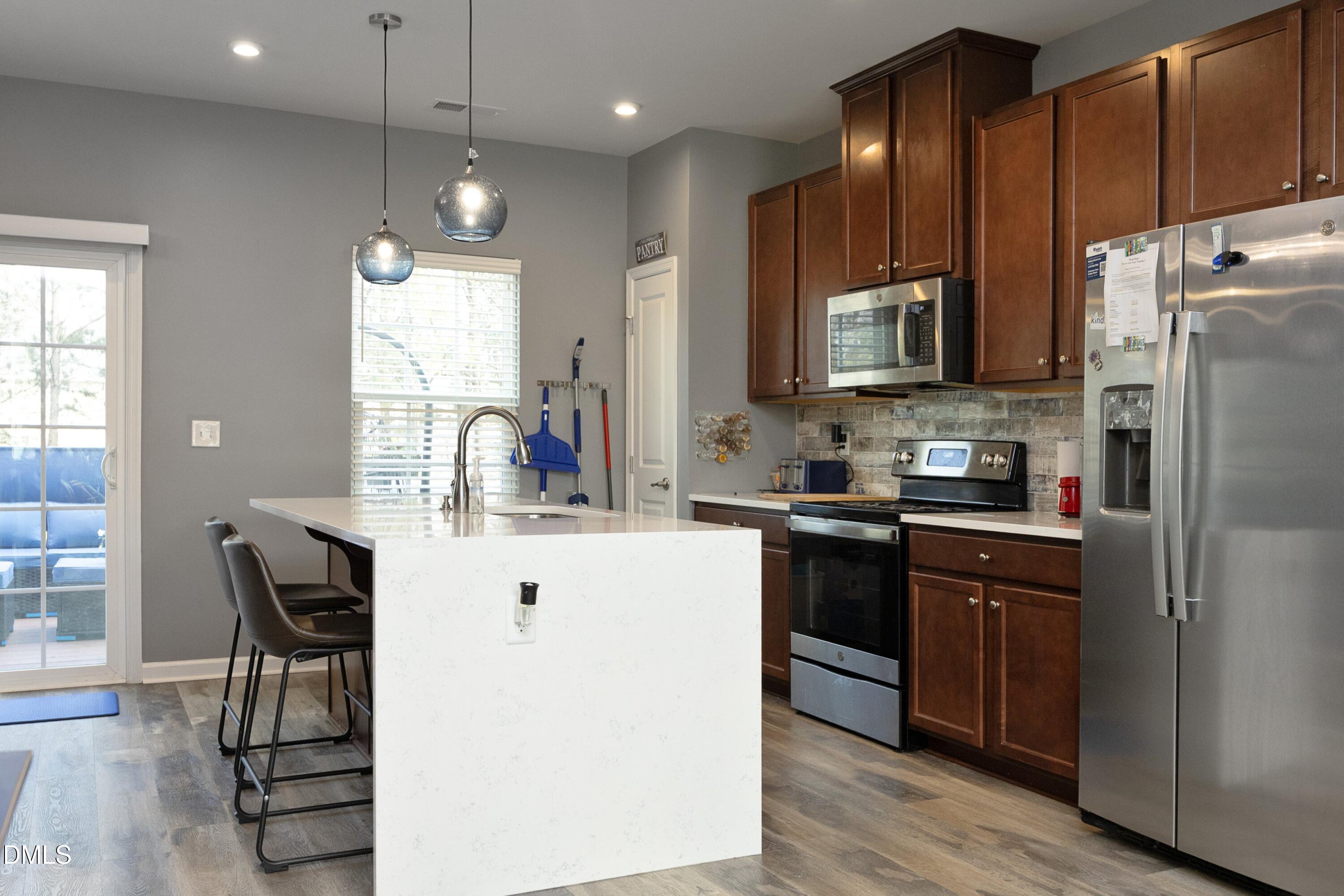 8716 Red Canyon Way Raleigh, NC 27616 - Photo 17 of 36 a kitchen with kitchen island granite countertop wooden floors stainless steel appliances a sink and a center island