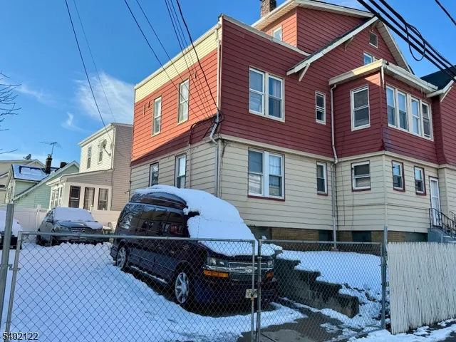 a front view of a house with barbeque and wooden fence