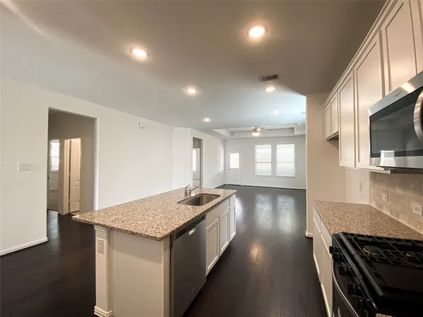 a open kitchen with kitchen island a sink stove and wooden floor