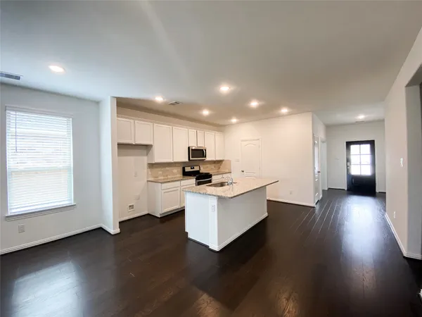 a living room with stainless steel appliances kitchen island hardwood floor sink and stove
