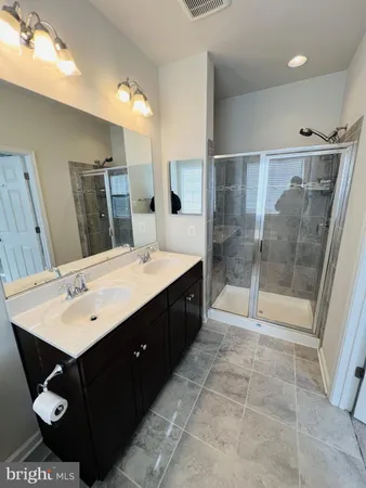 a bathroom with a double vanity sink mirror and shower