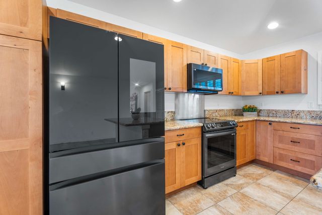 a kitchen with stainless steel appliances granite countertop a refrigerator and a stove top oven