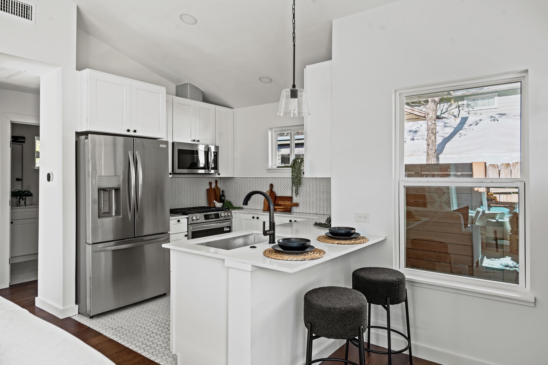 1006 Cherico Street, Unit 2 Austin, TX 78702 - Photo 5 of 7 Kitchen featuring stainless steel appliances, hanging light fixtures, white cabinetry, lofted ceiling, and a breakfast bar area