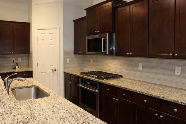 a kitchen with granite countertop a sink cabinets and stainless steel appliances