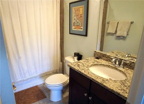 a bathroom with a granite countertop toilet sink and mirror