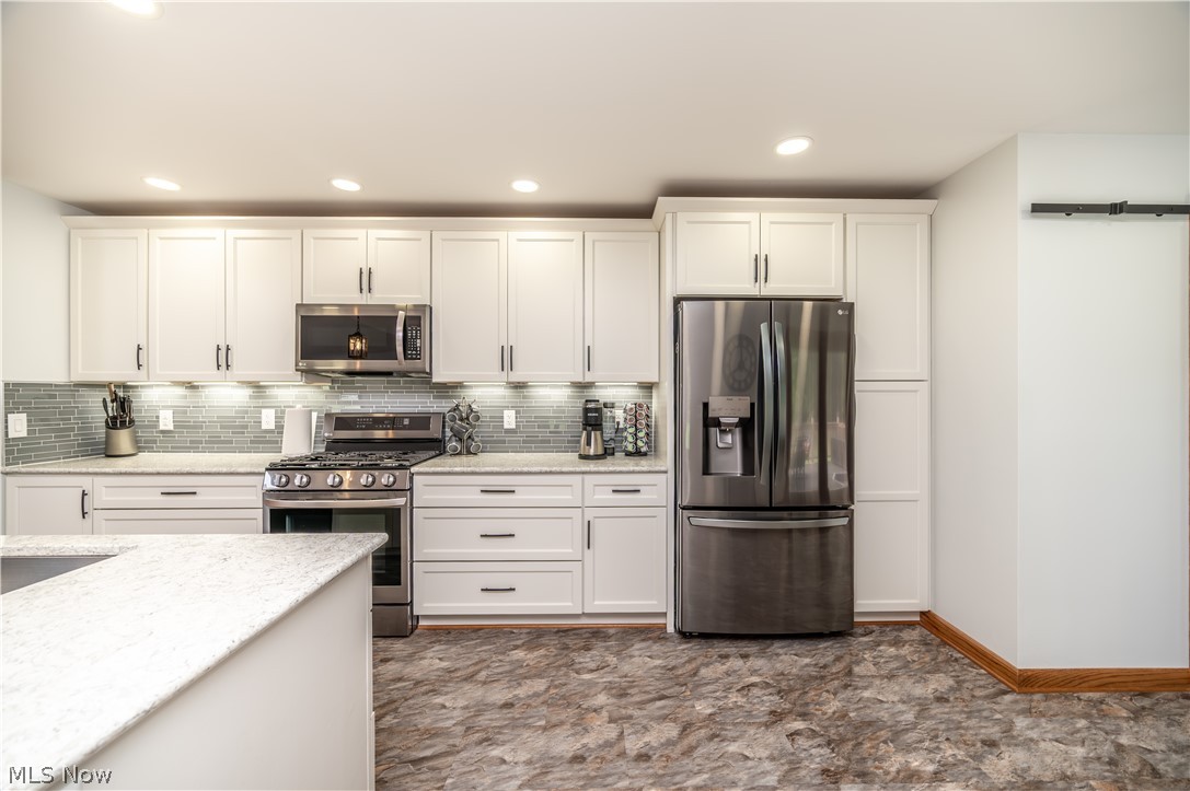405 Airport Road Northwest Warren, OH 44481 - Photo 14 of 50 Kitchen featuring white cabinetry, stainless steel appliances, a tile backsplash, and light-colored countertops