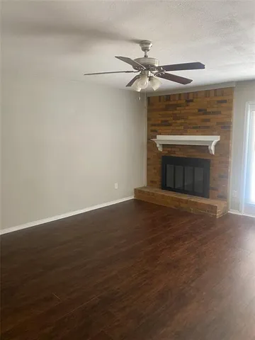 an empty room with wooden floor fireplace and fan