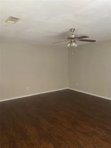 an empty room with wooden floor and fan