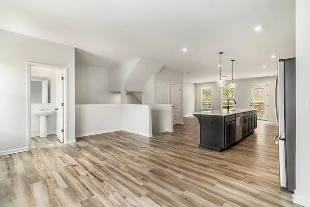 a large kitchen with kitchen island a sink dishwasher a stove and a refrigerator with wooden floor