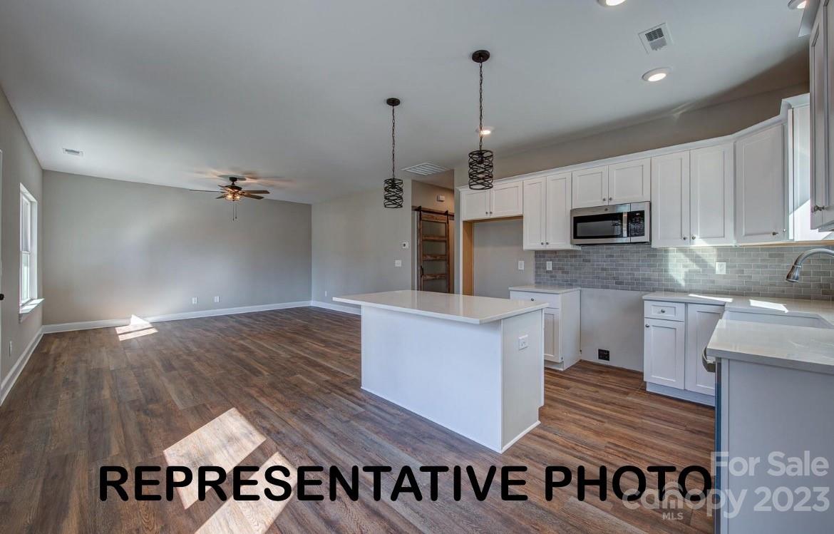 529 Blacksnake Road Stanley, NC 28164 - Photo 11 of 16 a kitchen with kitchen island granite countertop a stove a sink and a wooden floor