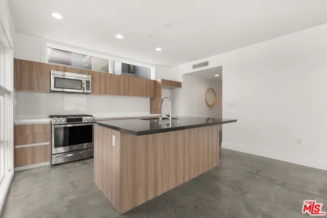 a kitchen with stainless steel appliances granite countertop a stove a sink and a microwave