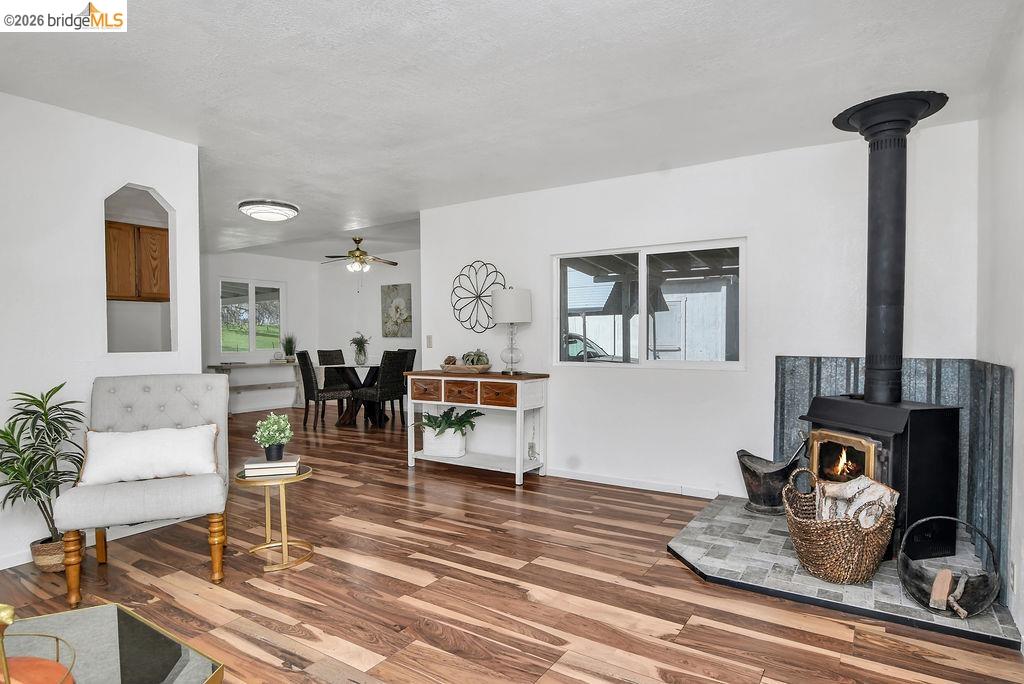 7550 Adams Road Valley Springs, CA 95252 - Photo 10 of 38 Sitting room featuring healthy amount of natural light, wood finished floors, a wood stove, and a ceiling fan
