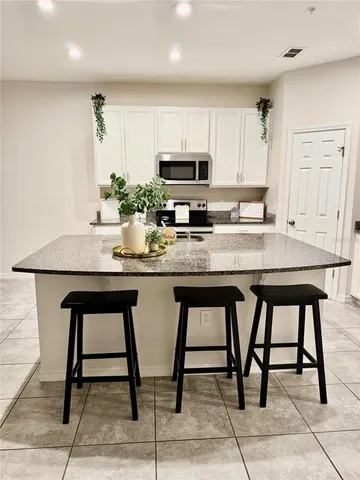 a kitchen with stainless steel appliances kitchen island granite countertop a table chairs sink and cabinets
