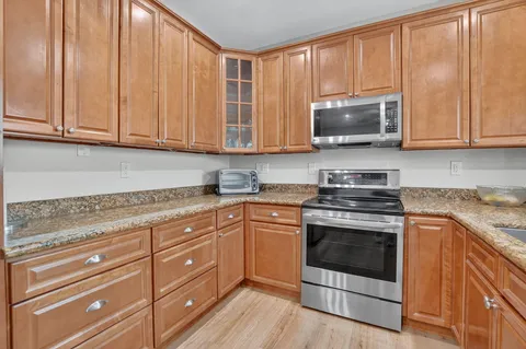 a kitchen with granite countertop cabinets stainless steel appliances and wooden floor