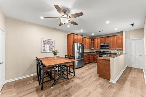 a kitchen with stainless steel appliances kitchen island granite countertop a table chairs and a refrigerator
