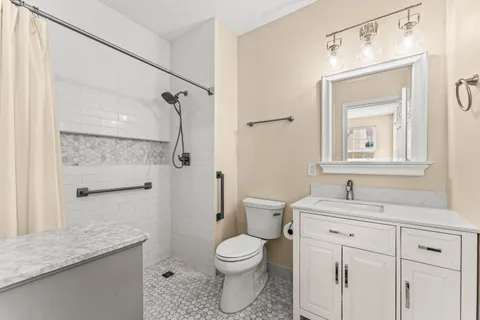 a bathroom with a granite countertop sink toilet a mirror and shower