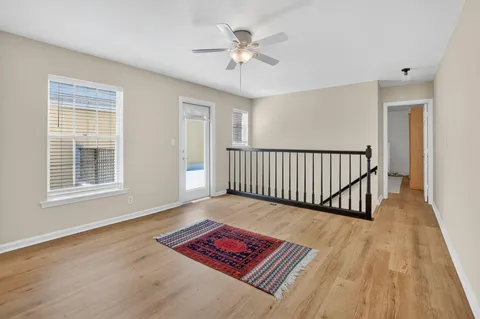 a view of a room with wooden floor a chandelier and windows