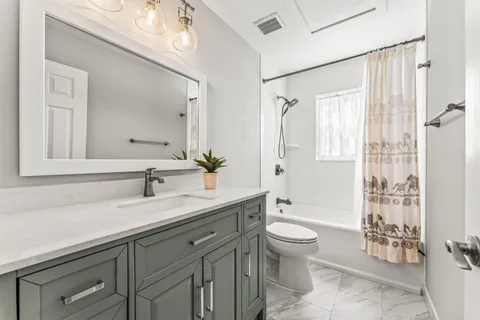 a spacious bathroom with a granite countertop sink a toilet a mirror and a shower